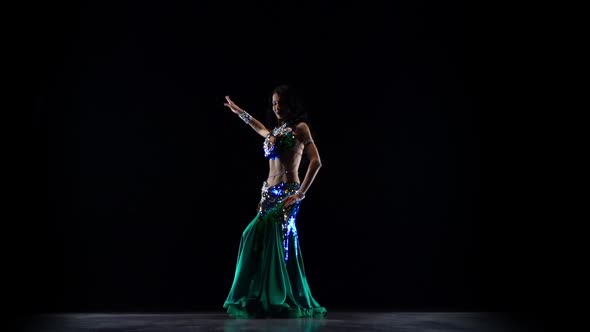 Girl Dancing in Green Dress on Black Background. Slow Motion