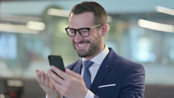 Portrait of Middle Aged Businessman Celebrating on Smartphone