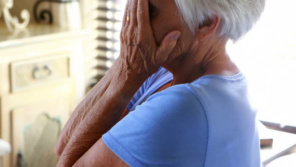 Stressed senior woman covering her face with hands