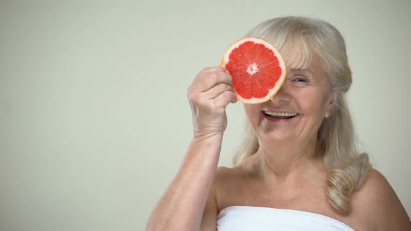 Cheerful Smiling Elderly Lady Closing Eye With Grapefruit Slice, Vivacity Charge