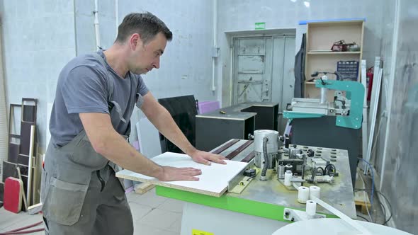 A man works on a machine that processes wooden workpieces in an assembly