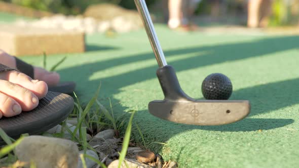 A Man in Sandals Putting on a Mini Golf Course, Close Up Slow Motion