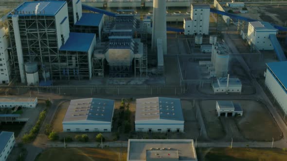 Aerial backwarding shot of Thar coal plant pumping power into national grid at sunset.