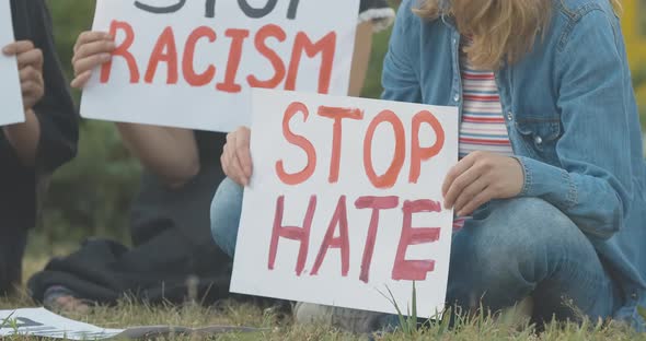 Stop Hate Placard in Female Hands Close-up. Unrecognizable Young Caucasian Protester Sitting on