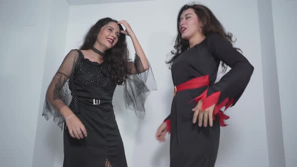 Two Excited Colombian Women Dressed In Black Halloween Costumes Celebrating Jumping And Bouncing On