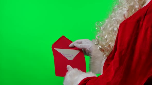 Santa Claus with a Beard in White Gloves and a Red Suit Is Holding an Envelope with a Letter From a