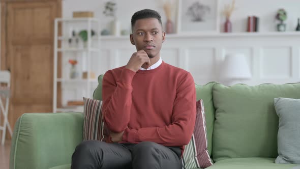 African Man Thinking while Sitting on Sofa