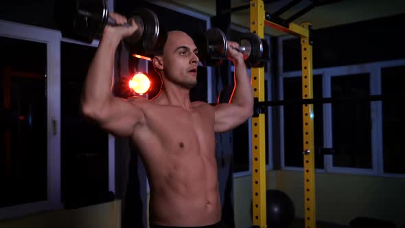 Bodybuilder Doing Overhead Press with Dumbbells in a Sports Club