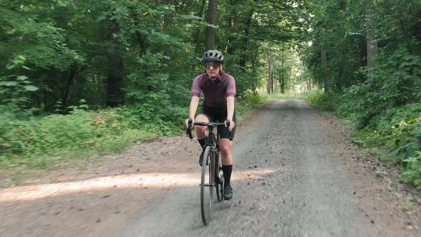 Cyclist cycling in helmet on bicycle on gravel road