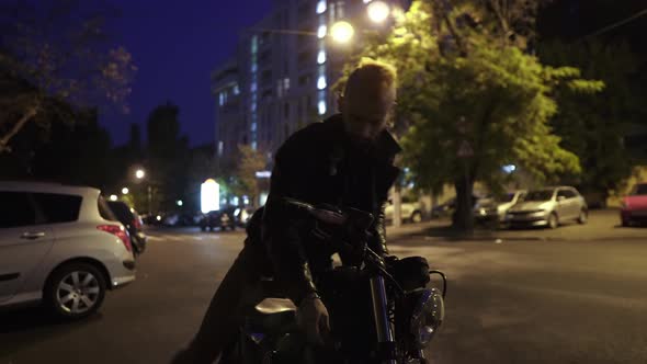 Handsome Rider Man Sitting on Classic Style Motorbike Turns on From Parking Place at Night