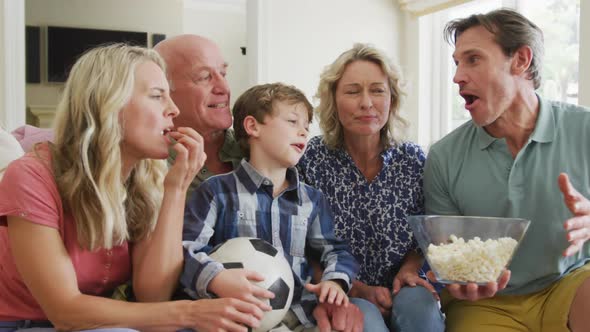 Happy caucasian family watching tv and supporting in living room