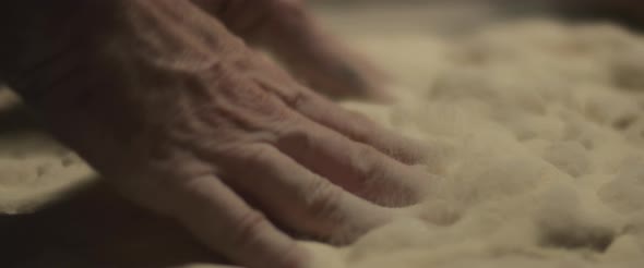 Chef preparing traditional pizza al taglio dough with his hands, slowly kneading dough.