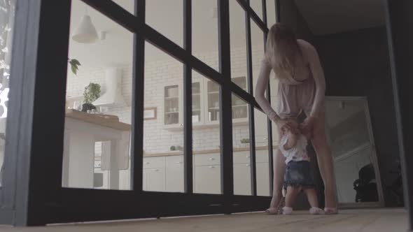 Young Woman and Her Baby Girl Standing on the Floor at Home