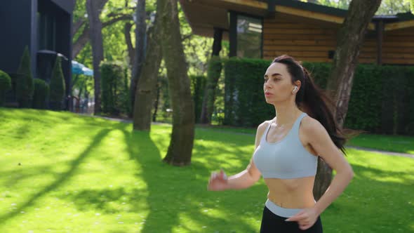 Slow Motion Female Jogger with Earphones in Park