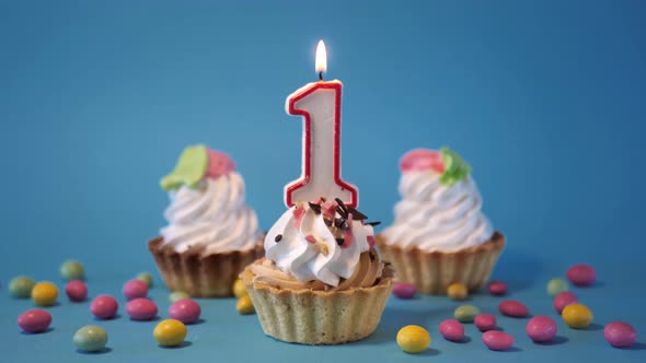 Cake Cupcake for Birthday with a Burning Candlenumber One 1 on a Blue Background