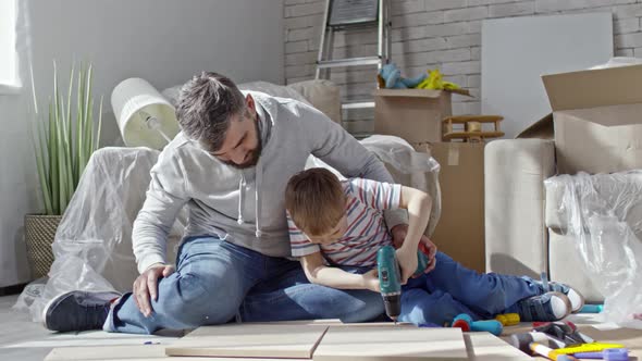 Father Teaching Son to Use Electric Screwdriver alt