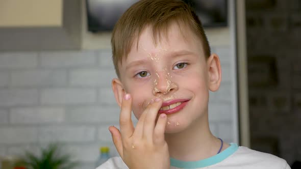Portrait of a happy cheerful Caucasian preschooler licks sweet cream off his face