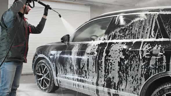 Worker at Car Wash Shop Using Pressure Washer on Car Man Washing Car with Compression Water