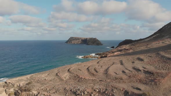 The northern cliff edged shore of Porto Santo and a remote road with another island in the distance.