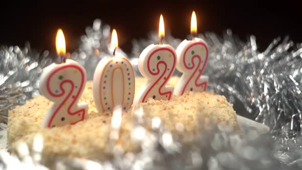 Christmas Cake Decorated with Burning Candles in the Form of the New Year 2022