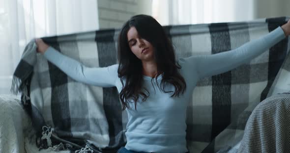 Young Depressed Woman Sitting Alone on Sofa, Hiding From World Under Plaid at Home