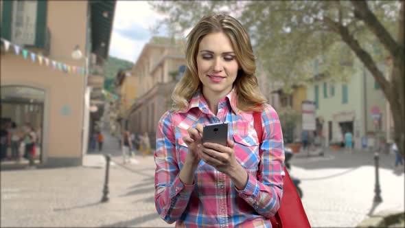 Smiling Caucasian Girl Using App on Her Smartphone