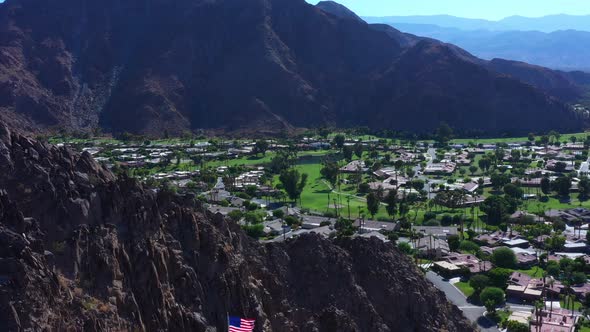 Aerial Tilt from Coachella Valley to USA Flag on top of Mountain