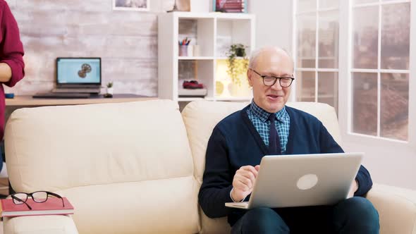 Grandparents with Glasses Sitting on Sofa Talking with Family