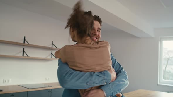 Caucasian couple very excited due to new house and embracing in their new flat.