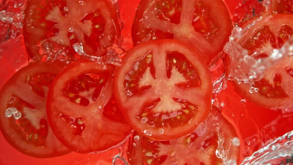 Super Slow Motion Shot of Tomato Slices Falling Into Water on Red Background at 1000Fps