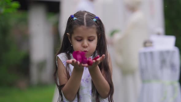 Charming Cute Middle Eastern Flower Girl Blowing Petals Smiling Looking at Camera