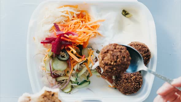 Timelapse Eating Falafel with Salad and Sauce in a Disposable Dish