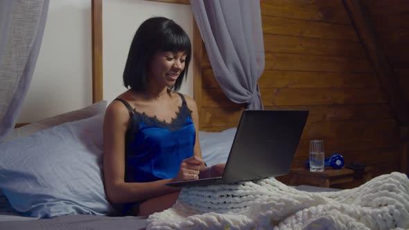 Woman Relaxing on Bed Using Laptop for Video Call