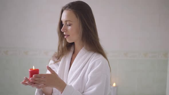 Sensual Romantic Young Woman Holding Candle Standing in Bathroom at Home Dreaming
