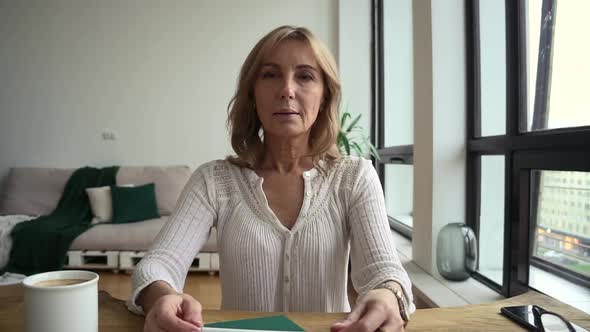 Woman Talking in Front of Screen and Sitting at Table in Home Room