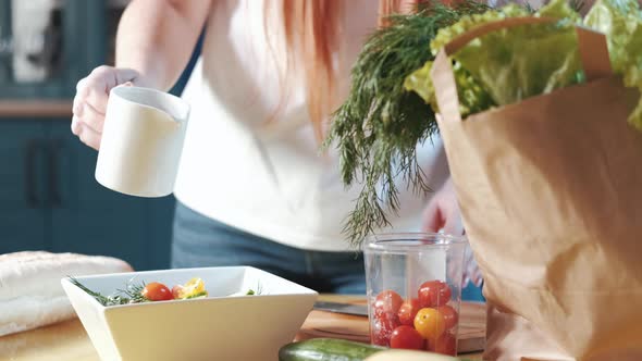 woman prepares a vegetable salad pours the sauce mix