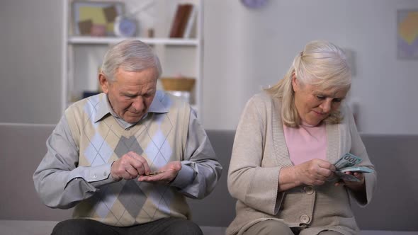 Old Man Counting Coins Looking at Happy Senior Woman Calculating Dollars, Wealth