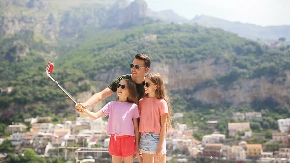 Father and Kids Taking Selfie Photo Background Positano Town in Itali on Amalfi Coast