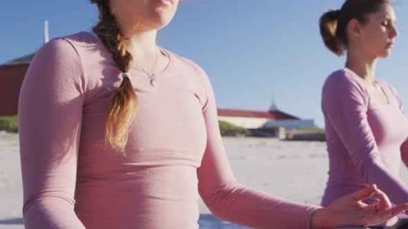 Multi-ethnic group of women doing yoga position on the beach and blue sky background