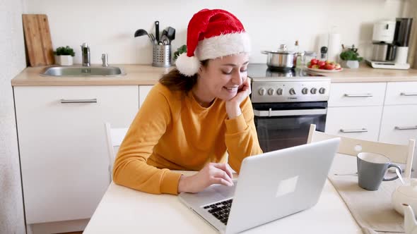 Smiling Girl Wearing Santa Hat Waving Hand Video Calling Family By Webcam