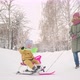 A happy mom rides a joyful toddler 15-23 months old on a snowcat sled - VideoHive Item for Sale