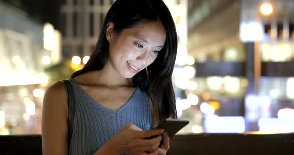 Woman using mobile phone in the city at night 