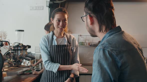 Female barista worker hands show gesture with menu on tablet and talk to customer at cafe restaurant