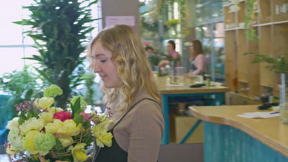 A Girl with Blond Wavy Hair Holds in Her Hands a Luxurious Bouquet of Flowers of Different Colors
