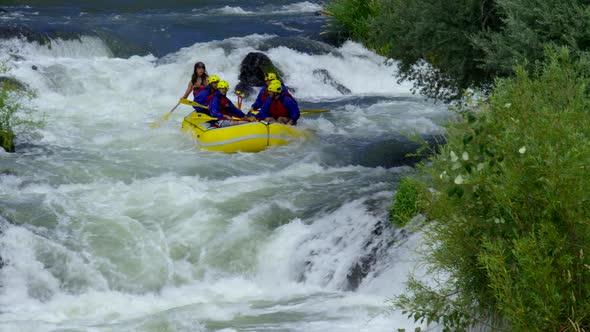 Group of people white water rafting off waterfall