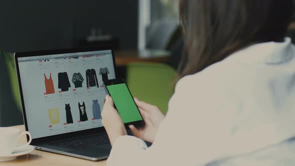 Close-up of Woman Looking To Her Phone with Chromakey at Clothes Website in Laptop on Background