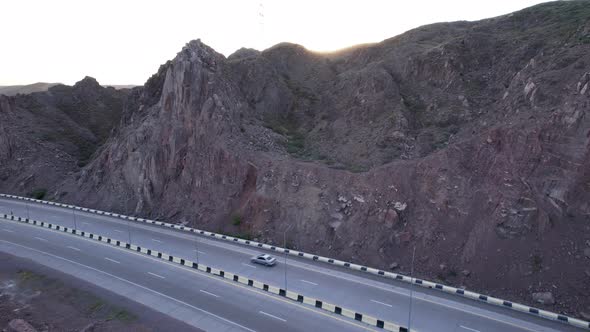 Cars Drive Along the Highway Among the High Rocks