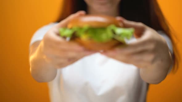 Girl Showing Beef Burger to Camera, Temptation by Fast Food, Unhealthy Eating