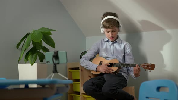 Boy Of Ten Sitting In The Nursery With Guitar In His Hands