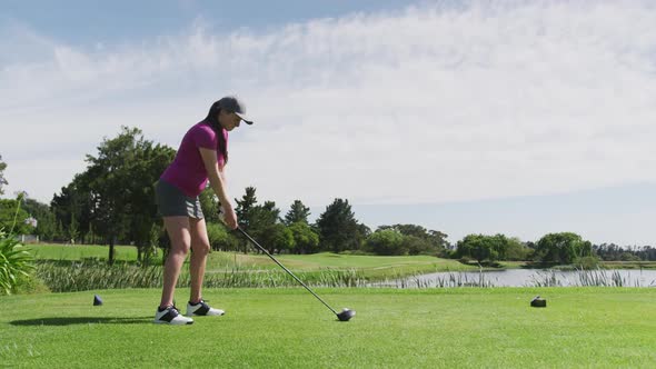 Caucasian woman playing golf taking a shot from bunker